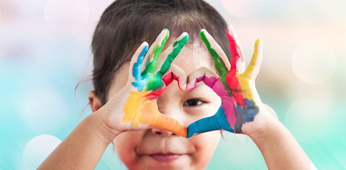 A child with painted hands making a heart shape